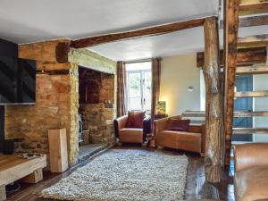 a living room with a stone wall with a couch and chairs at Juniper Cottage in Hook Norton