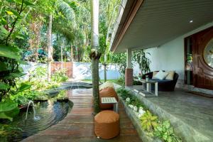 a patio with a pond and a couch and trees at Pool Villas by Honey - Luxury Family Resort-8 km from Beach & Nightlife in Nong Prue
