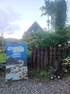 a sign sitting next to a wooden fence at Banna Cafe & Glamping บ้านนา คาเฟ่ แอนด์ แกรมปิ้ง in Fang