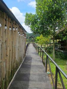 a wooden fence with a walkway next to a tree at Banna Cafe & Glamping บ้านนา คาเฟ่ แอนด์ แกรมปิ้ง in Fang +28 photos