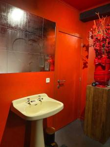 a bathroom with a white sink and a red wall at Romantic house with hot tub in Poelkapelle +27 photos
