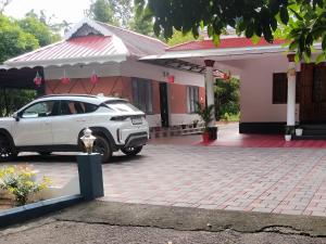 a white car parked in front of a house at ETERNA Homestay Rackad in Mūvattupula +5 photos