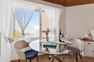 a dining room with a glass table and chairs and a window at Lake View Studio 1 - 2 Personen I See - Bergsicht I 40" Smart TV I Dusche, Fahrstuhl und Parkplatz in Ingenbohl +17 photos