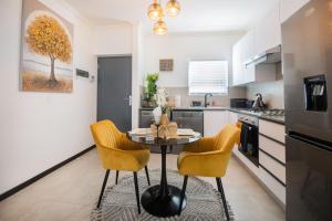 a kitchen with a table and two yellow chairs at Deplatinum Luxury Apartment-A Home away with love in Sandton