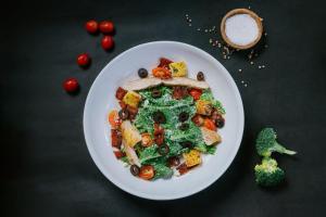 a white plate of food with vegetables on a table at Dewangga Suite in Ubud +1 photo