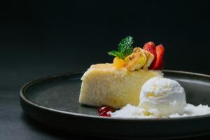 a piece of cake with strawberries and ice cream on a plate at Dewangga Suite in Ubud