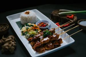 a plate of food with meat and rice on a table at Dewangga Suite in Ubud
