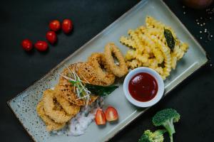 a plate of food with onion rings rice and vegetables at Dewangga Suite in Ubud
