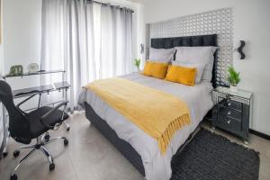 a bedroom with a bed and a desk and a chair at Deplatinum Luxury Apartment-A Home away with love in Sandton +21 photos