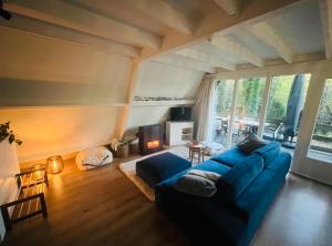 a living room with a blue couch and a large window at De Wegwam Durbuy in Septon