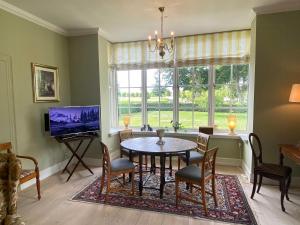 RingeにあるManor House Overlooking Fields And Gardenのテーブルと椅子とテレビのあるダイニングルーム