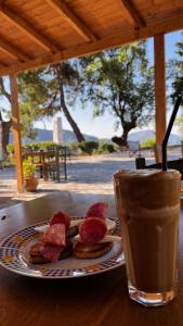 a plate of meat and a cup of coffee on a table at ANDRIANA Mountain Home - ASPRIAS 