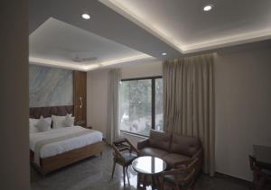 a hotel room with a bed and a couch and a window at Hotel V K Grand in Kannauj