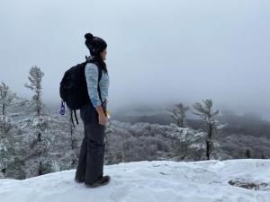une femme avec un sac à dos debout au sommet d'une montagne enneigée dans l'établissement Cozy Tented Cabin Rental near the Hudson River in Upstate New York, à North River
