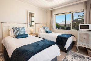 two beds in a room with a window at Stylish OceanBreeze 50 Central Mossel Bay in Mossel Bay