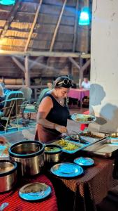 een vrouw die eten bereidt op een tafel met borden eten bij LIMAS Camp Mikumi in Mikumi
