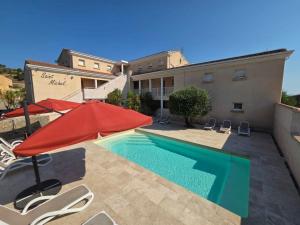 a swimming pool with a red umbrella and chairs and a building at Résidence Saint Michel in LʼÎle-Rousse