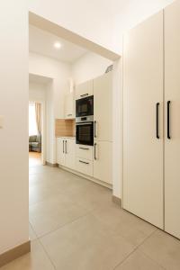 a kitchen with white cabinets and black appliances at Stilvolles Altbau Apartment - 2 Min zur U-Bahn, Nähe Donaukanal in Vienna