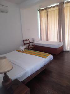 a room with two beds and a chair in it at Oga Reach Yala in Lukasgoda +12 photos