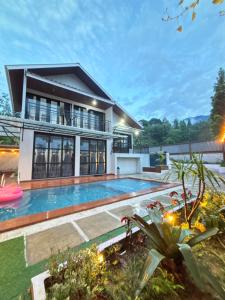 a villa with a swimming pool in front of a house at Villa Andira Hidden Paseban in Pondok Cipaseban