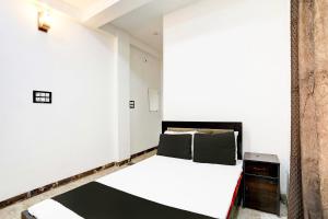 une chambre avec un lit blanc et une armoire en bois dans l'établissement Hotel O Raj Mahal, à Jabalpur