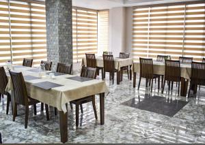 a dining room with tables and chairs and windows at Hotel GaiaYuel in Thimphu