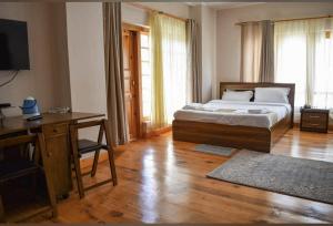 a bedroom with a bed and a desk and a television at Hotel GaiaYuel in Thimphu