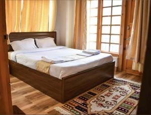 a bed in a bedroom with a window and a rug at Hotel GaiaYuel in Thimphu