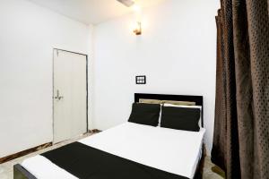 - une chambre avec un lit blanc et des oreillers noirs dans l'établissement Hotel O Raj Mahal, à Jabalpur