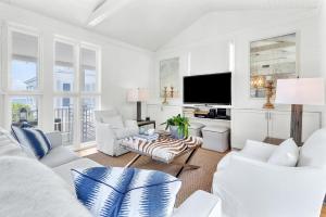 a living room with white furniture and a flat screen tv at On the Beach in Santa Rosa Beach