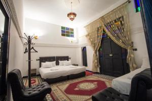 a bedroom with two beds and a chair and a door at ROOM iN FES MEDINA in Fès