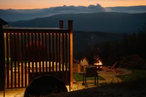 a woman sitting at a table next to a fire at Brvnara Vila Promaja in Kladovo