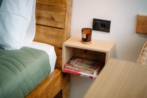 a bed with a nightstand with a cup and books at Brvnara Vila Promaja in Kladovo