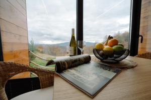 a book on a table with a bowl of fruit and a bottle of wine at Brvnara Vila Promaja in Kladovo