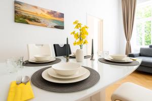 a white table with bowls and plates on it at Stilvolles Altbau Apartment - 2 Min zur U-Bahn, Nähe Donaukanal in Vienna +4 photos