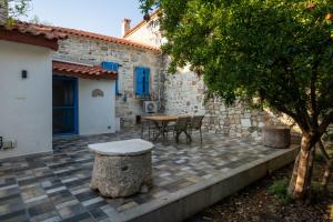 a patio with a table and chairs next to a building at MINIQ HOMES 103 - Stone House with Garden Cinema, Barbecue, Mini Golf in Foca