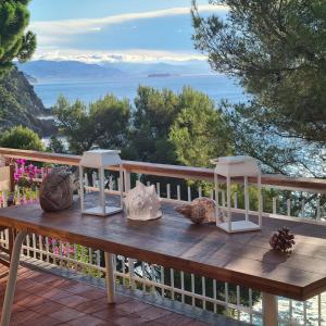 a wooden table on a balcony with a view of the ocean at Villa Cokkinis in Varazze