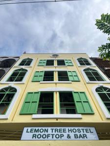 a yellow building with green windows and a sign on it at Lemon Tree Hostel Khaosan in Bangkok +59 photos