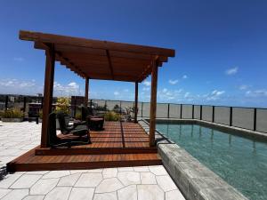 eine hölzerne Pergola neben einem Pool in der Unterkunft Experiência a beira mar, Jacuzzi e conforto in Água Boa