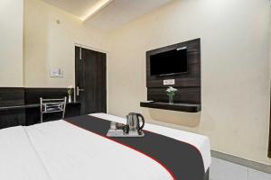 a hotel room with a bed and a flat screen tv at Hotel O Unique Stay Inn in Bādshāhnagar