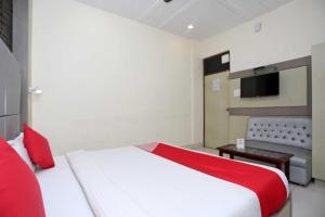 a bedroom with a red and white bed and a tv at Hotel O Unique Stay Inn in Bādshāhnagar +10 photos