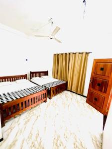 a room with two beds and a dresser at Monkey Garden Hotel in Polonnaruwa
