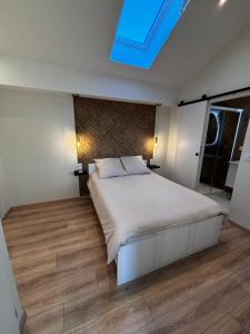 a bedroom with a large white bed and a skylight at Appartement cosy une chambre in Charnècles