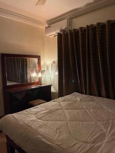 een slaapkamer met een bed, een bureau en een raam bij Two Bedrooms Standby Generator DSTV Netflix W-iFi in Takoradi