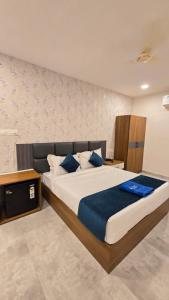 a bedroom with a large bed with blue pillows at Elite Hotel Karimnagar in Kottapalli