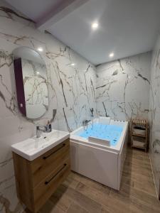 a bathroom with a white sink and a marble wall at Les secrets de l Esch in Jezainville
