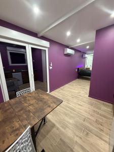 a living room with a wooden table and purple walls at Les secrets de l Esch in Jezainville
