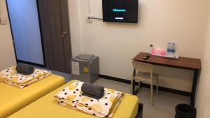 a room with two beds and a desk and a television at 731 Hostel Victory Monument in Sathani Sam Sen