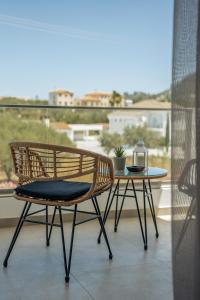 a rattan chair and a table on a balcony at Phōs, Light Modern Living in Gaïtánion