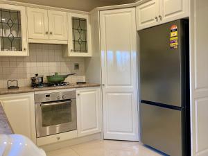 een keuken met witte kasten en een roestvrijstalen koelkast bij Hillside Retreat with Pool in Flagstaff Hill